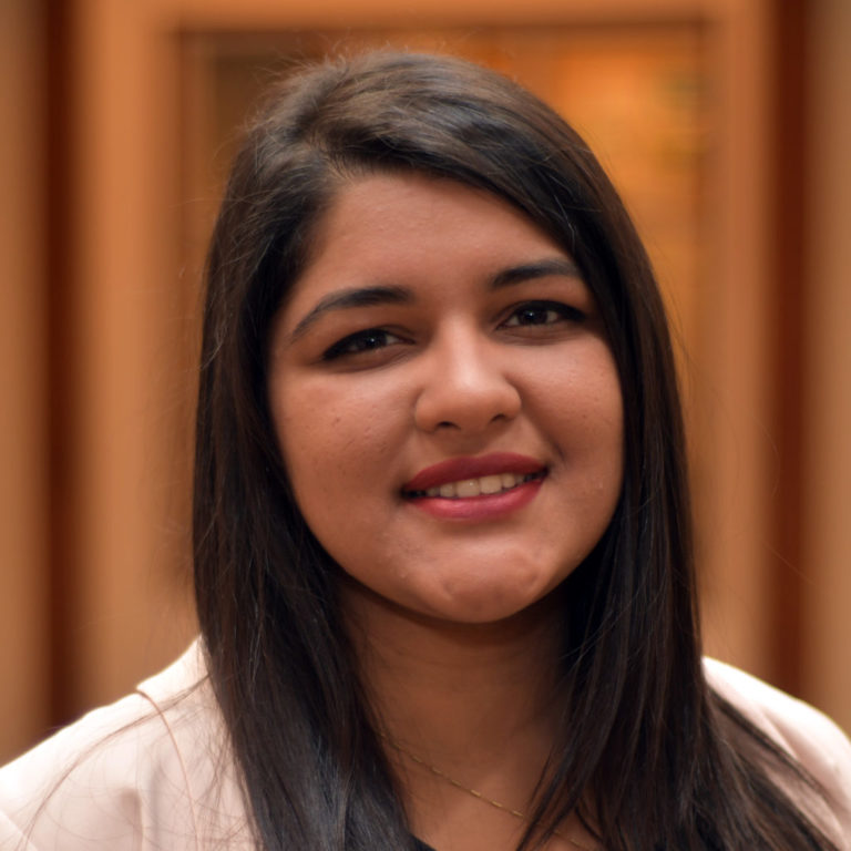 woman looking at camera smiling in front of brown background